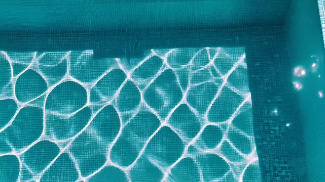 Summer hot vibe lifestyle. A topdown view of a swimming pool reveals the intricate patterns and textures of the waters surface. The water is a vibrant turquoise.