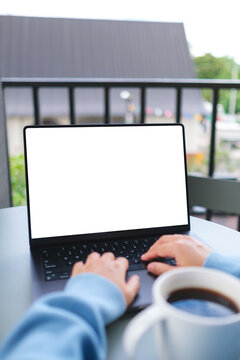 Vertical mockup image of a woman working and typing on laptop computer with blank white desktop screen in cafe