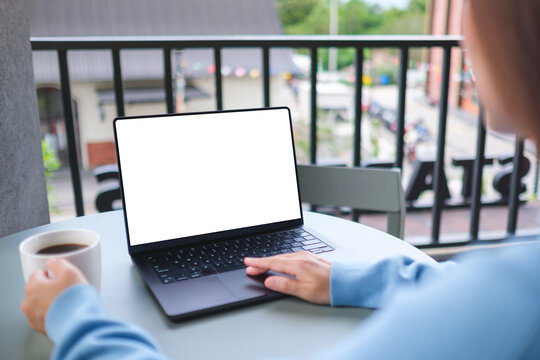 Mockup image of a woman working on laptop computer with blank white desktop screen while drinking coffee in cafe