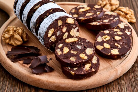 Chocolate salami slices on wooden board with walnuts