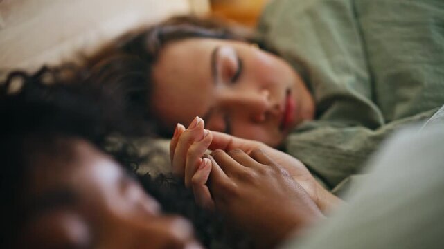 Close up lesbian couple sleeping bed together. Interracial women resting home.