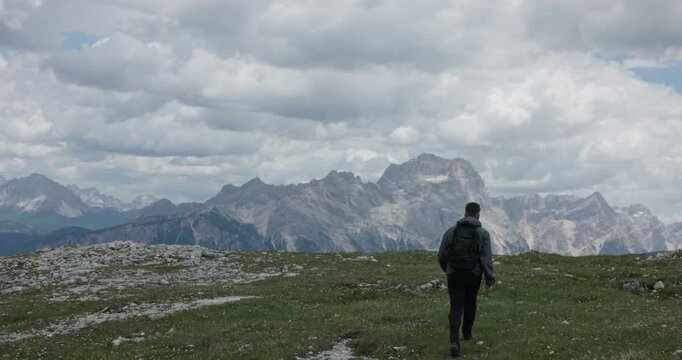 A Man With A Backpack Walks Along A Mountain Trail At Cinque Torri Near Cortina d'Ampezzo In The Dolomites Of Northern Italy. Slow Motion Shot