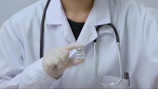 Confident professional doctor wearing white coat stethoscope holds medical nad therapy vial using protective latex glove for clinical treatment