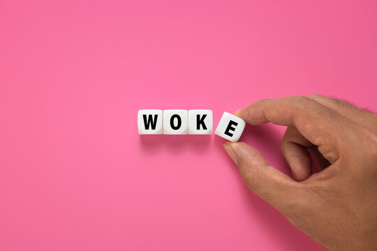 male hand put cubes with woke word symbol isolated on pink background