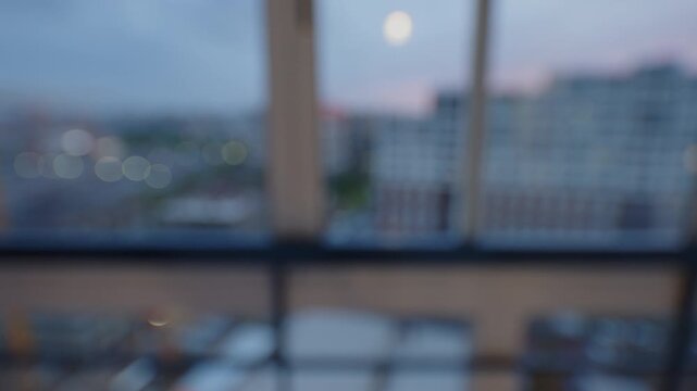Defocused view from a balcony toward a construction site and apartment buildings at dusk