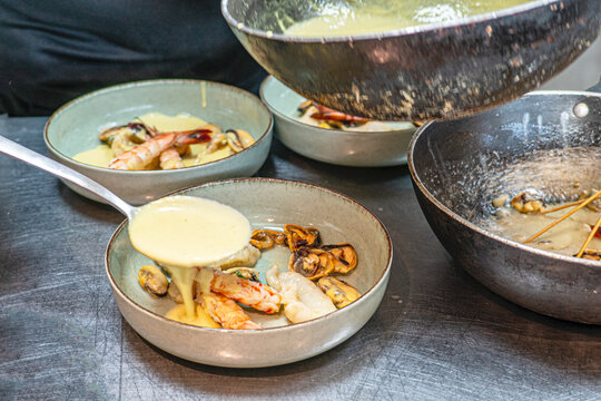 Chef is preparing Mediterranean Seafood Platter with Grilled Fish, Shrimps, Mussels, and Dipping Sauce