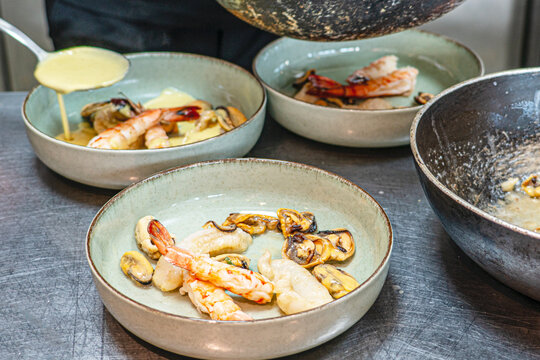 Chef is preparing Mediterranean Seafood Platter with Grilled Fish, Shrimps, Mussels, and Dipping Sauce