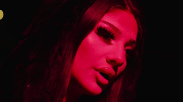 Young woman using a vape under dramatic red neon lighting. Ideal for nightlife, vaping, party, club, fashion, and atmospheric concepts.