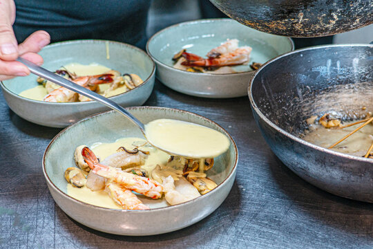 Chef is preparing Mediterranean Seafood Platter with Grilled Fish, Shrimps, Mussels, and Dipping Sauce