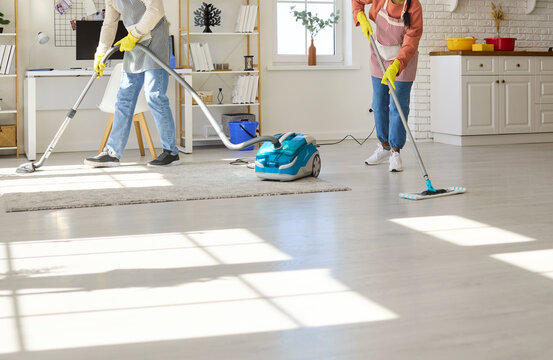Couple cleaning home vacuuming and mopping chores together. Bright apartment interior shows shared responsibility and efficient housekeeping with mop and vacuum. Theme of hygiene and teamwork.