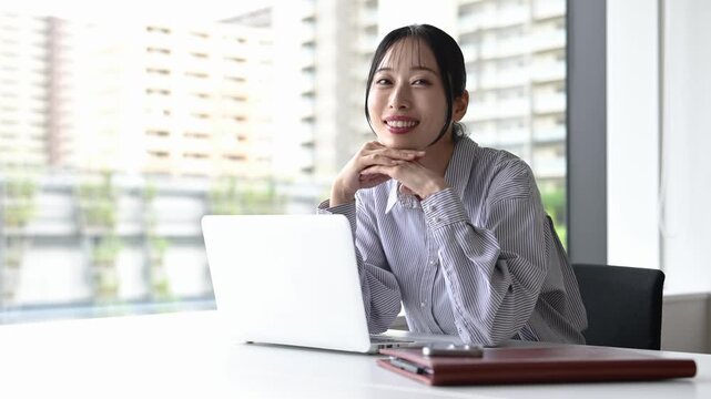 窓際でノートパソコンを使って仕事をする30代の日本人ビジネスパーソンの女性