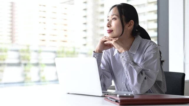 ノートパソコンを使いながらリラックスする30代日本人女性