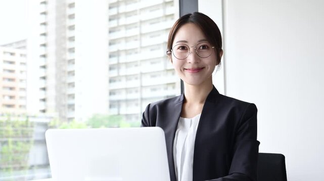 眼鏡をかけて笑顔でノートパソコンを使う20代日本人女性