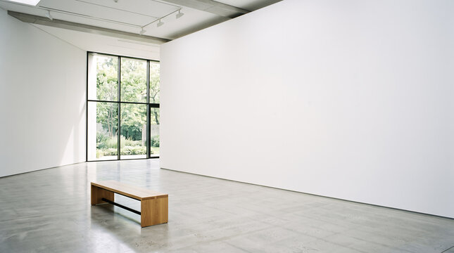 Oak bench in a white gallery beside a tall window onto greenery