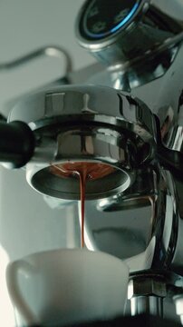 4K Pouring coffee stream from professional machine in cup. Barista man making double espresso, using filter holder. Flowing fresh ground coffee. Drinking roasted black coffee in the morning.