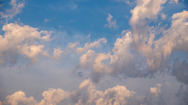 Dramatic cumulus clouds in blue sky with warm evening light 