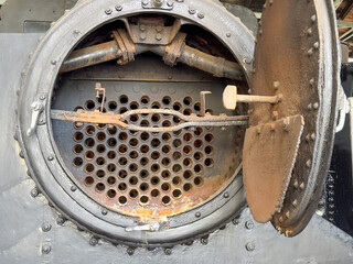 Vintage steam locomotive boiler. Close-up of open smokebox showing rusty fire tubes and pipes of an old train mechanism © Yulia Antonova