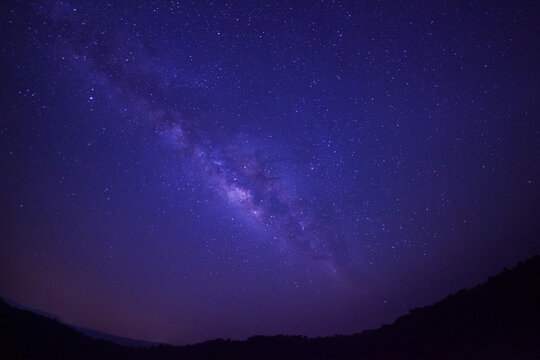 Silhouette of mountain at Phuhinrongkla national park and night sky space background, Starry universe in dark blue sky, Milky way galaxy with stardust field in deep universe