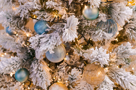 Close Up of a Flocked Christmas Tree with Blue and Gold Baubles