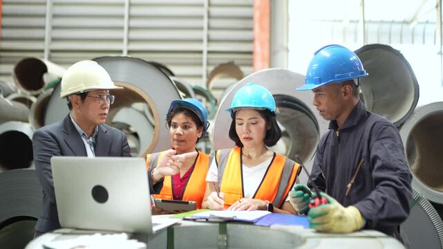 Industrial inspection team checking steel coil inventory and quality records in manufacturing warehouse. Material verification, factory operations and production management.