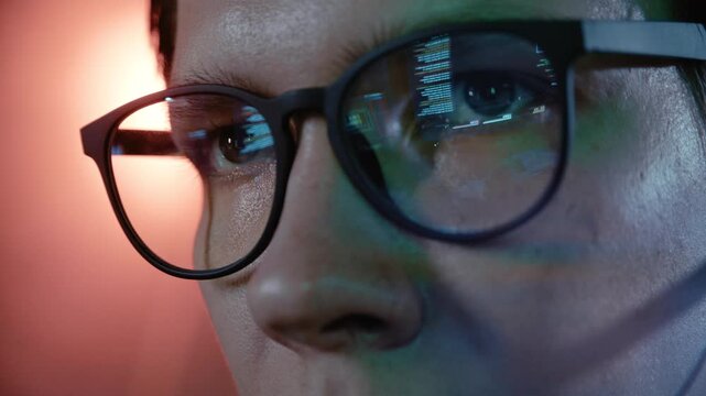 Close up of a computer programmer's glasses reflecting lines of programming code from a monitor