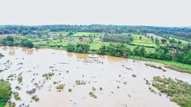 Drone view of flooded landscape with murky water covering fields and vegetation areas