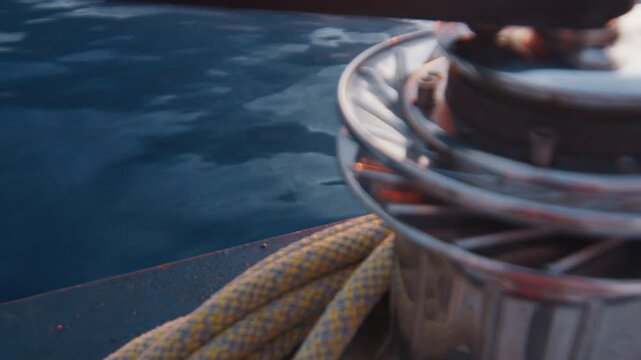 Winch with rope of the sailing boat moving in the ocean. Sunset as seen from the moving sailing boat with winch on the foreground