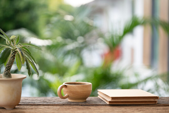 brown wooden cup and brown notebook and Dorstenia plant arranged on wooden table