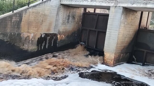 Dirty wastewater rushing through concrete sluice gate for water pollution and environmental management themes