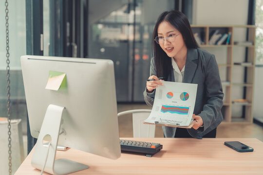 Asian businesswoman showing financial chart on clipboard during online video conference call on tablet.