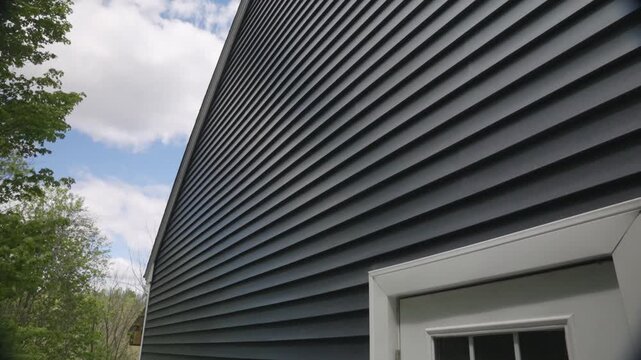 Slow motion tilt up of newly installed siding on an Aframe house with blue sky