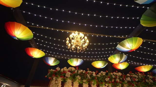 Indian wedding sangeet stage decoration. Colorful umbrellas and fairy lights at night.