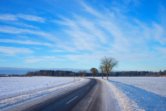 Road curve with slush. Cleared country road in winter, dangerous slipperiness.
