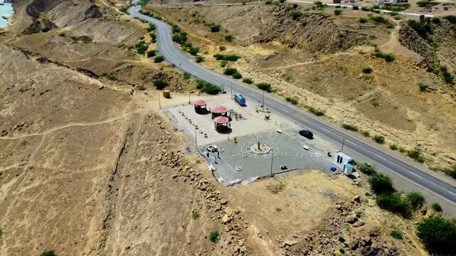 Stunning aerial footage over Kund Malir&rsquo;s roadside rest stop, showcasing rugged mountains, arid terrain, winding highway, and the scenic beach coastline under bright daylight drone video.