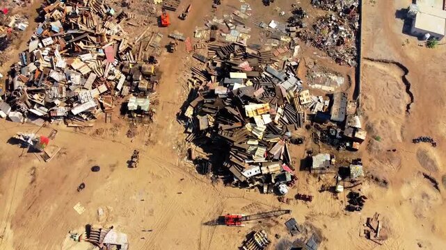 Aerial drone footage over Gadani shipbreaking yard near Karachi, Pakistan. Rusty scrap metal, beached ship, industrial machinery, and polluted shoreline highlight ocean waste and environmental impact.