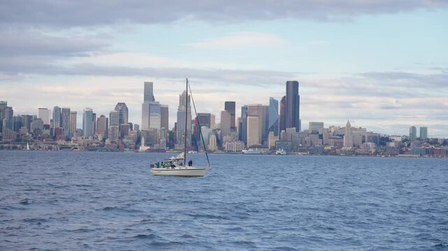 A sailboat crosses Elliott Bay as the camera pans to follow it in slow motion, with the Seattle skyline stretching along the horizon, Panning Shot