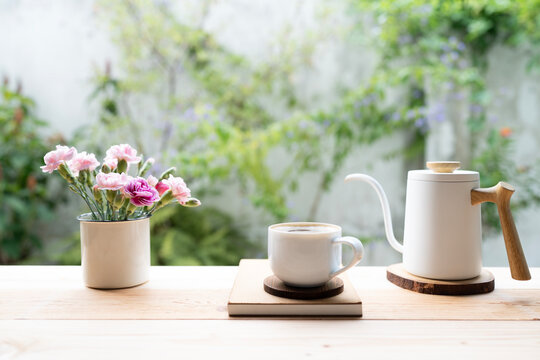 tea cup and pink carnation flowers and white kettle on wooden table