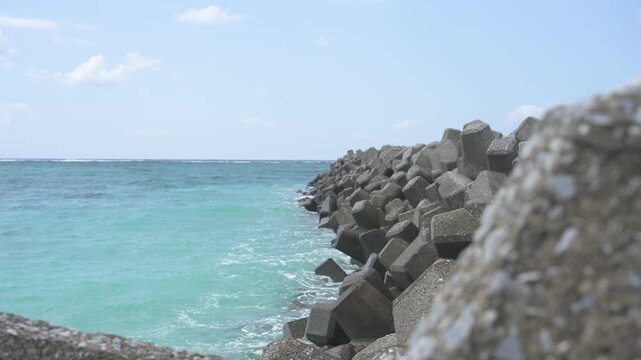 手前の消波ブロック越しに眺めるエメラルドグリーンの美しい海