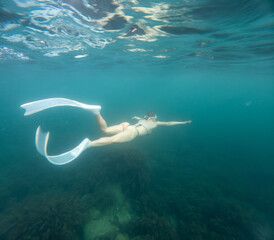 Long fins, woman swimming underwater in turquoise sea with white flippers and bikini during apnea dive © panophotograph