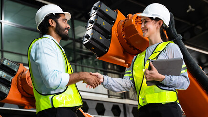 Fototapeta premium Professional engineering team celebrating successful inspection and maintenance activities with a handshake inside an advanced automated manufacturing facility.