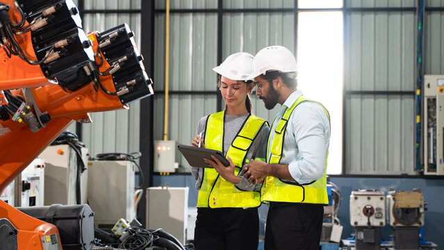 Engineering professionals carrying out equipment assessment and quality inspection while discussing robotic automation systems inside a manufacturing plant.
