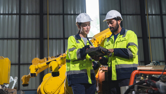 Professional engineers inspecting automated manufacturing equipment while reviewing quality records and maintenance planning inside a smart factory.