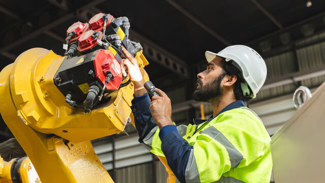 Professional engineer performing a final inspection on the robot end effector to verify equipment condition and production readiness inside a modern manufacturing plant.