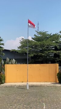 Indonesian Flag Waving on Flagpole Against Blue Sky Vertical Video