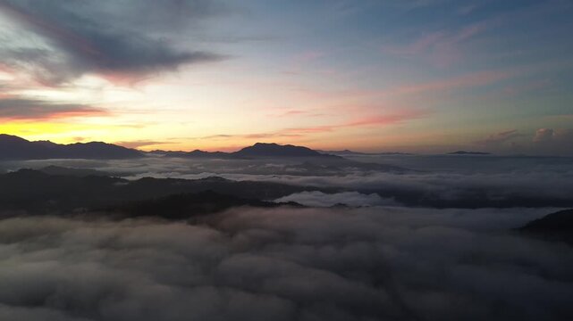 Aerial View of Sunrise Over Mountain Peaks Above Clouds