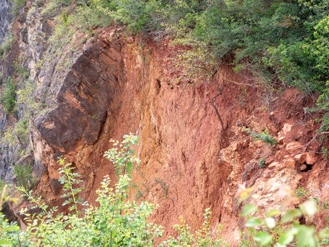 Close-up of a colorful weathered rock wall with red clay and exposed limestone layers at the Velk&aacute; Amerika quarry in the Bohemian Karst, Czech Republic.
