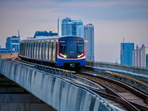 Bangkok, Thailand - July 8, 2026 :  The BTS Skytrain runs in and out of Ha Yaek Lat Phrao Station in the evening, offering views of office buildings and beautiful scenery. illustrative