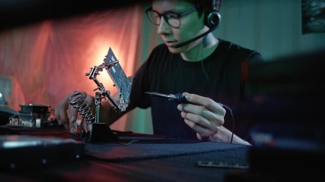 An electronics specialist assembles or repairs a circuit board using professional soldering tools.