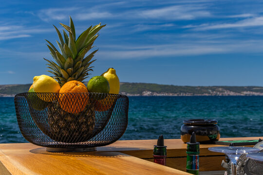 Fresh tropical fruits in wire basket on seaside bar counter for cocktails and refreshing drinks