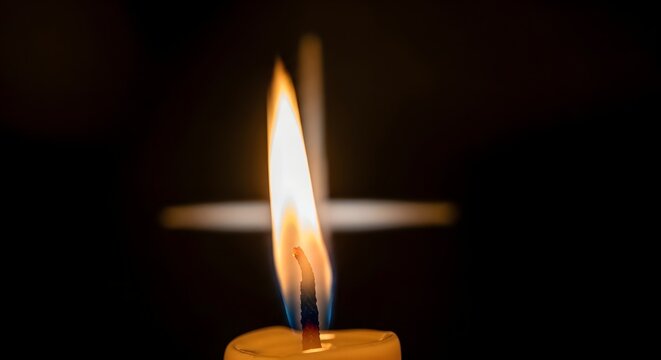 Burning candle flame in dark foreground with blurry christian cross background for prayer and faith concepts